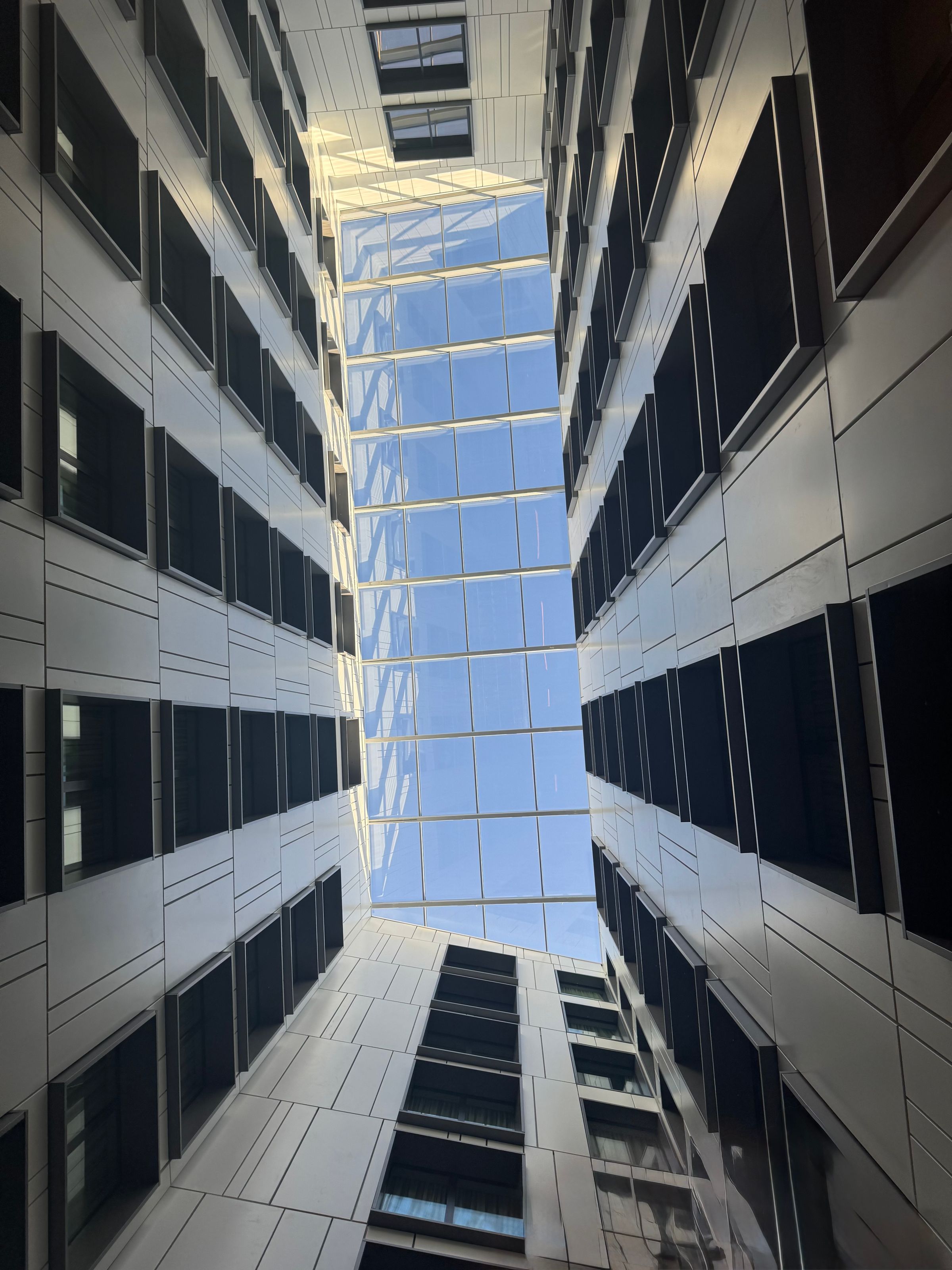 Looking upward through a glazed courtyard with repeated windows; illustrative architecture, not an Avantti project